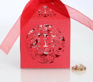Detail of red hollowed-out Chinese wedding candy box with silk ribbon and rhinestone