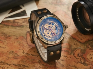 Nahaufnahme einer automatischen Skelettuhr aus Bronze mit schwarzem Lederarmband.