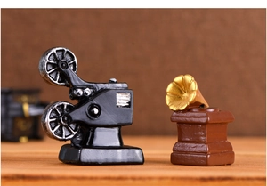 Detail of miniature vintage movie projector and gramophone on a wooden surface