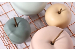 Primer plano de manzanas decorativas de cerámica Morandi en cesta de oro rosa