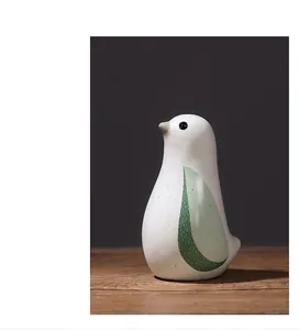 Nahaufnahme eines nordischen Vogel-Keramik-Ornaments mit Glasur auf Holzsockel