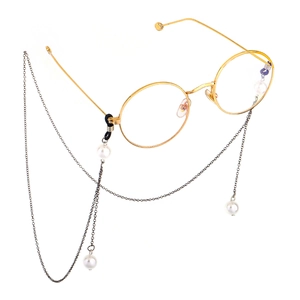 Detailed close-up of golden round frame glasses with elegant white pearl hanging chain