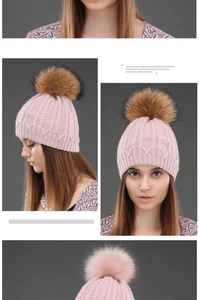 Detail view of pink cable-knit beanie with a large brown faux fur pom-pom for winter warmth