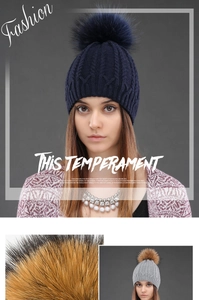Close-up of winter knit hat with large fur pompom and classic cable stitch texture