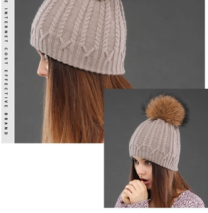 Detail of cable knit beanie with large fur pom-pom showing warm winter ear protection