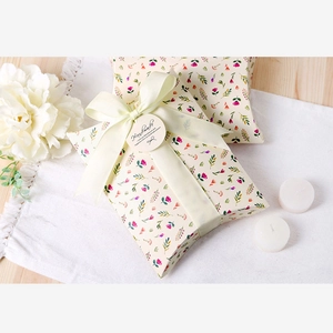 Floral print pillow box with beige ribbon and handmade tag on white linen