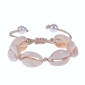 Detail of bohemian woven shell bracelet with white pearls and adjustable beige cord