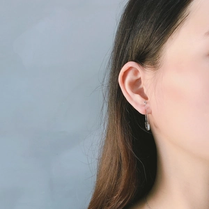 Close-up of a silver safety pin earring on model with polished mirror finish details