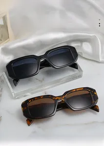 Detail of vintage thick rectangular sunglasses in black and tortoiseshell on marble stand
