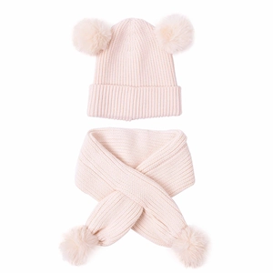 Detail of pink knitted baby hat and scarf set with soft fluffy pom-poms for winter