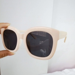 Detail view of square frame sunglasses featuring a cream finish and dark lenses