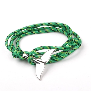 Macro detail of multicolored braided rope bracelet with a silver whale tail charm
