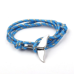 Detail of adjustable blue braided rope bracelet with silver whale tail charm