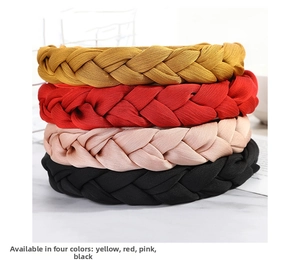 Close-up of braided wide headbands in yellow red pink and black on marble surface