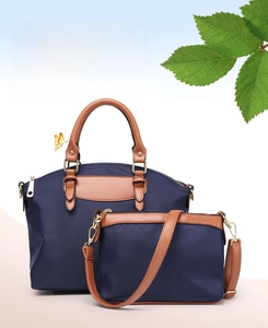 Detail view of the deep blue nylon tote bag with brown leather handles and golden metal hardware