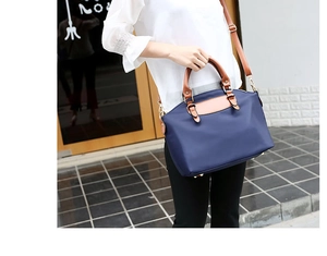 Detail of navy nylon Boston bag with brown leather handles and gold metal hardware
