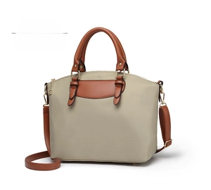 Detailed side view of apricot nylon handbag with brown handles and gold hardware