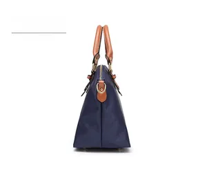 Detail of navy nylon tote bag showing brown leather trim and golden metal hardware