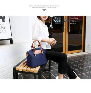 Detail of durable navy nylon tote bag with brown leather handles and a long shoulder strap