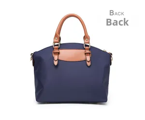 Detail view of the back of a navy oxford nylon tote bag with brown leather handles