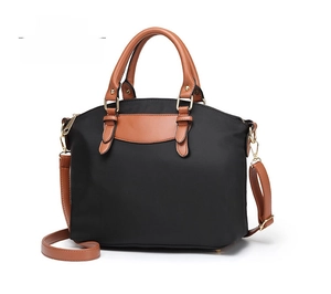 Side view of black nylon handbag with brown leather straps and gold metal details