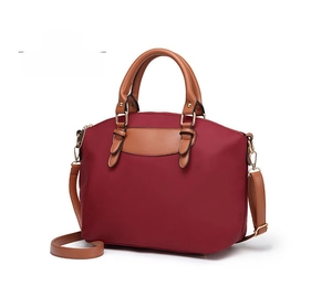 Detail view of red oxford fabric dumpling bag with brown handles and shoulder strap
