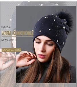 Close-up of pearl and rhinestone details on warm knit hat with fluffy faux fur pompom