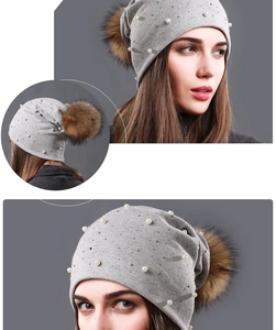 Detail of light gray beanie with pearls, rhinestones and large fluffy fur pompom