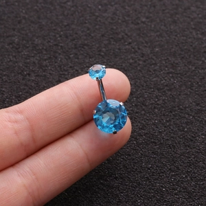 Detailed view of a stainless steel belly button ring with a blue zircon gem inlay