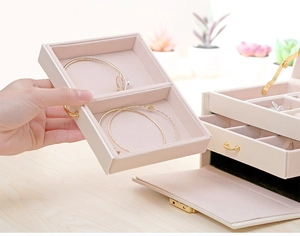 Detail view of drawer inside beige PU leather jewelry box with pink velvet lining and compartments