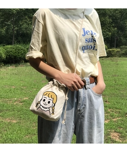 Close-up of cream canvas drawstring bucket bag with cute cartoon girl illustration