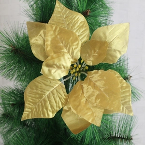 Detail of golden poinsettia artificial flower decoration on Christmas tree needles