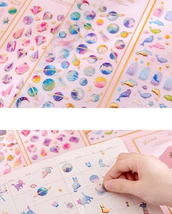 Close-up of golden foiled unicorn stickers being applied to a creative DIY diary