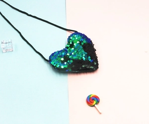 Detail of heart-shaped flip sequin coin purse for kids with adjustable black lanyard strap