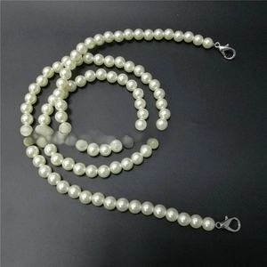 Macro detail of creamy faux pearl chain with metallic silver lobster clasps for bags