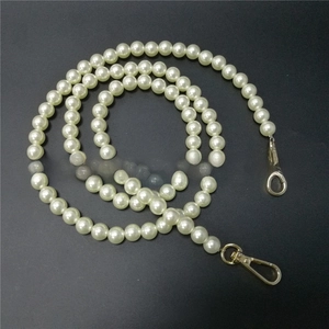 Detailed view of round white pearl chain with golden lobster clasps for bags and phones