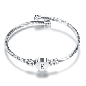 Detail view of silver twisted rope cuff bracelet with heart pendant featuring letter E