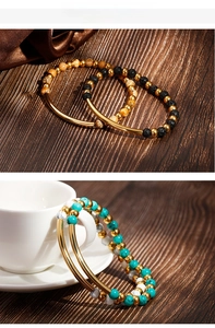 Detail of beaded turquoise and lava stone bracelets with polished gold metal tube