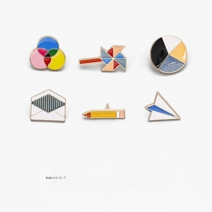 Set of 6 colorful enamel pins featuring pencil, paper plane, and geometric shapes