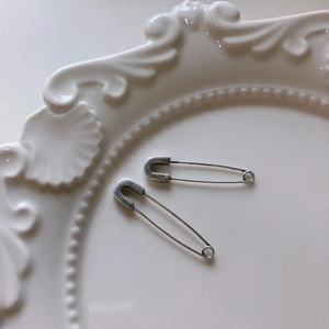 Retro S925 sterling silver safety pin earrings with matte finish on vintage ceramic plate