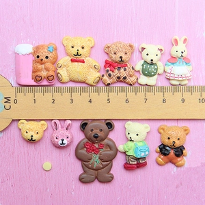 Cartoon resin bear and rabbit DIY charms on pink background with measuring ruler