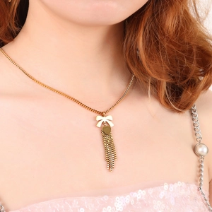 Collana con nappine a fiocco dorato e pendente a cuore su modella, set gioielli moda