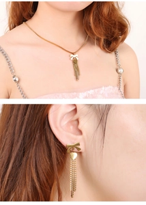 Dettaglio del set collana con fiocco dorato e nappa a cuore con orecchini coordinati