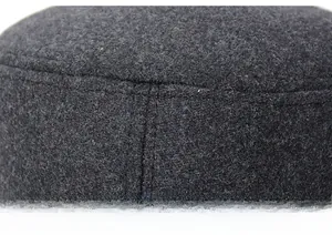 Close-up of high-quality thick dark grey wool fabric with detailed stitching on flat top cap