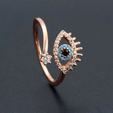 Macro detail of rose gold Evil Eye ring with inlaid blue and white crystals