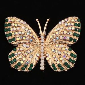 Macro shot of a golden butterfly brooch with colorful rhinestones and white pearls