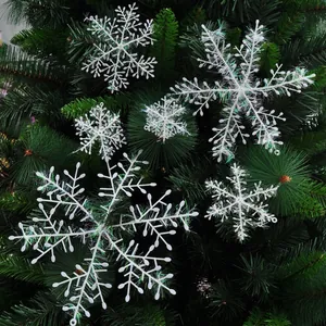 Sparkling white Christmas snowflake ornaments with iridescent tinsel on tree branches