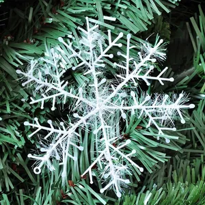 White iridescent glitter snowflake ornament hanging on a green Christmas tree branch