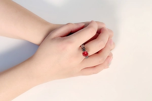 Detailed close-up of a vintage silver ring featuring a round red gemstone on a hand