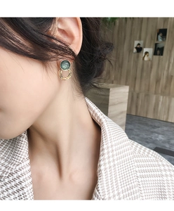 Close-up of retro dark green resin stud earring with gold wire on a model's ear